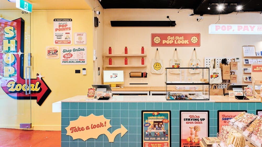 A bright and inviting interior of POP Canberra, featuring a checkout counter, merchandise,.