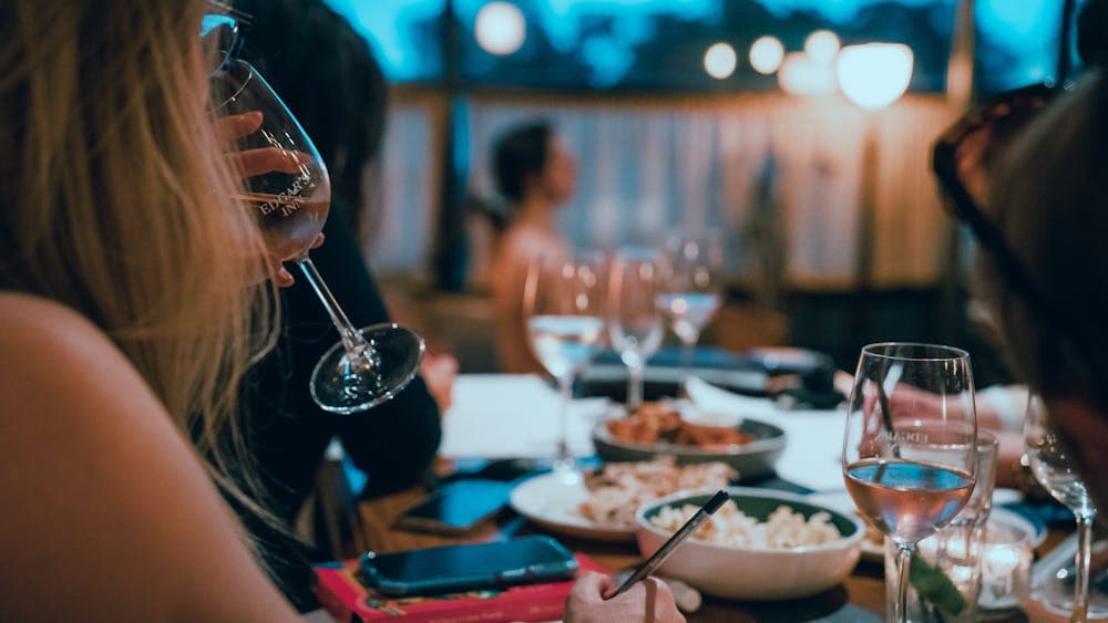 Woman drinking sparkling wine with art model sitting in background