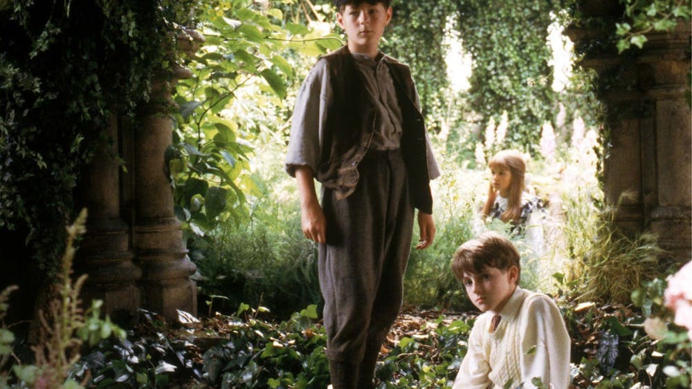 Three young children sitting within a garden
