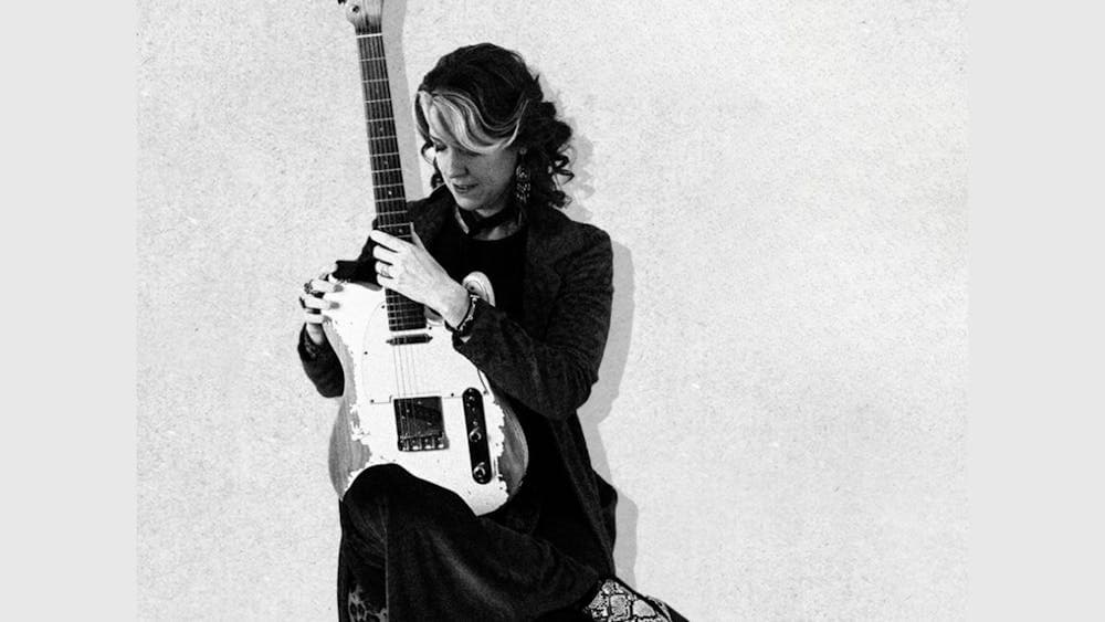 A lady sitting holding a guitar
