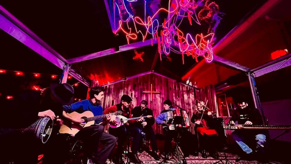 A band sitting in a line in a room with colourful lights
