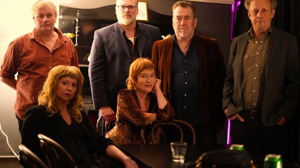 6 musicians, 4 are standing and 2 are sitting in front