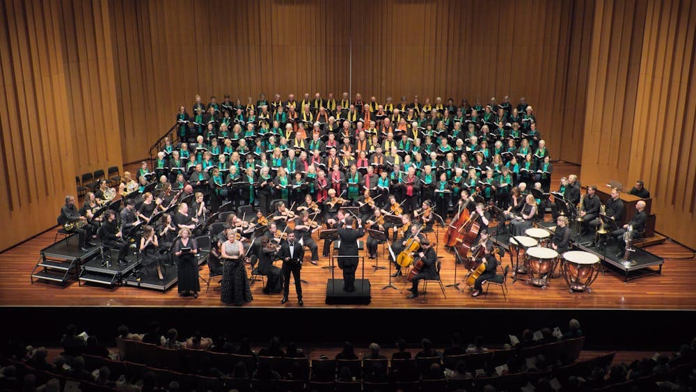 Choir and orchestra on stage with conductor, two female and one male soloist. auience in foreground