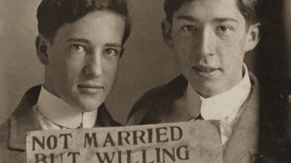 Two men holding a sign that reads 'NOT MARRIED BUT WILLING TO BE.'