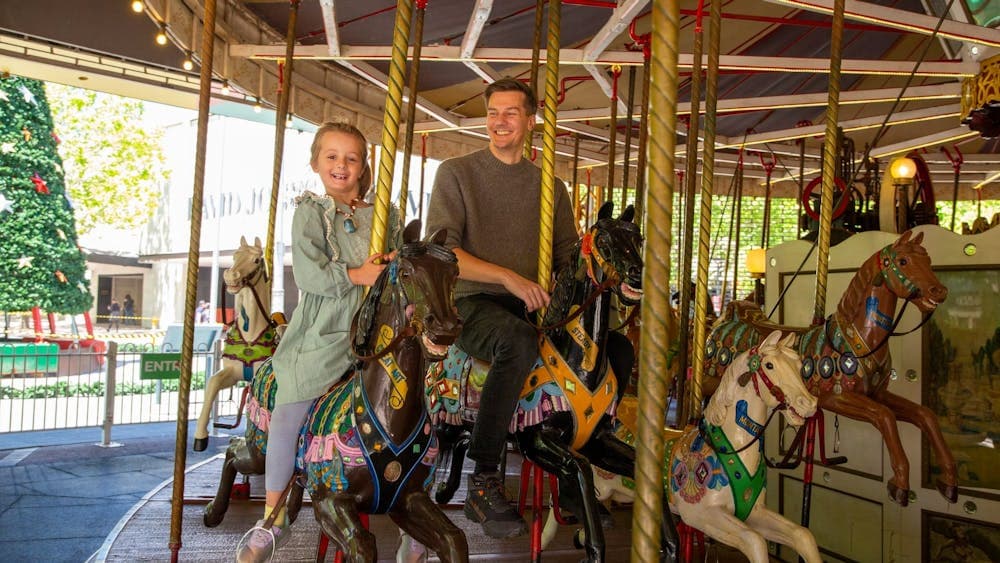 A man and a young girl riding Canberra's historic merry-go-round