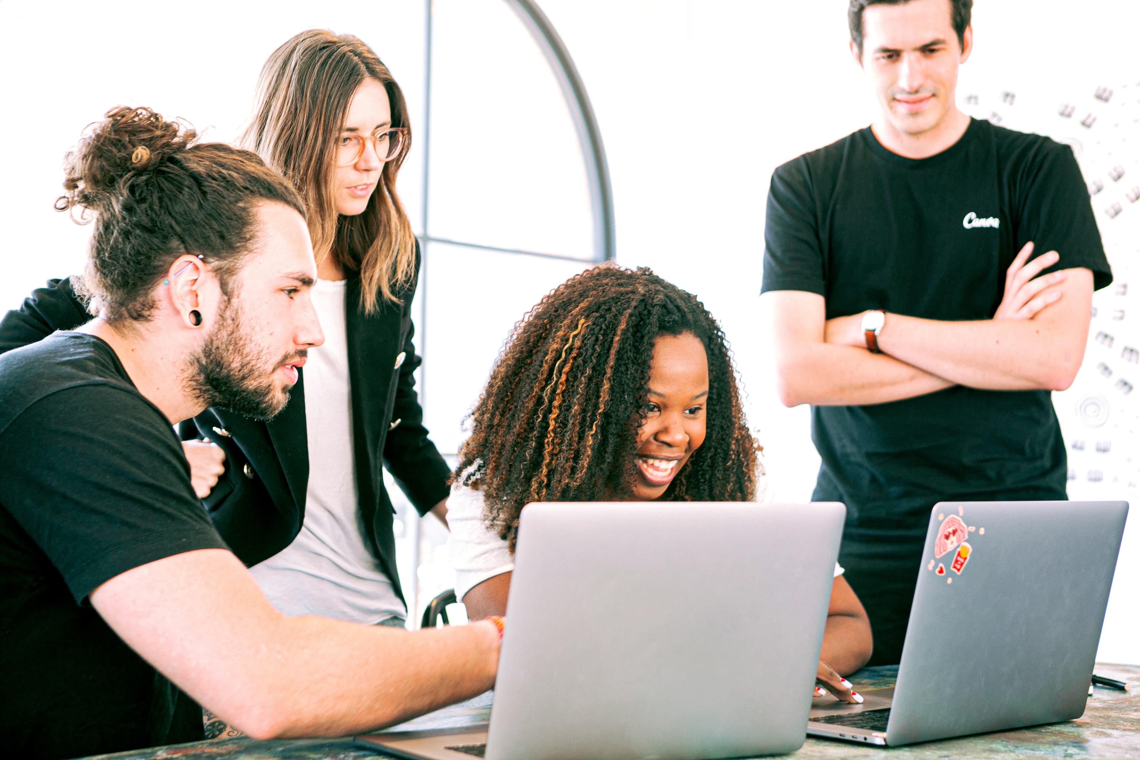 Group of four adults working on laptops.