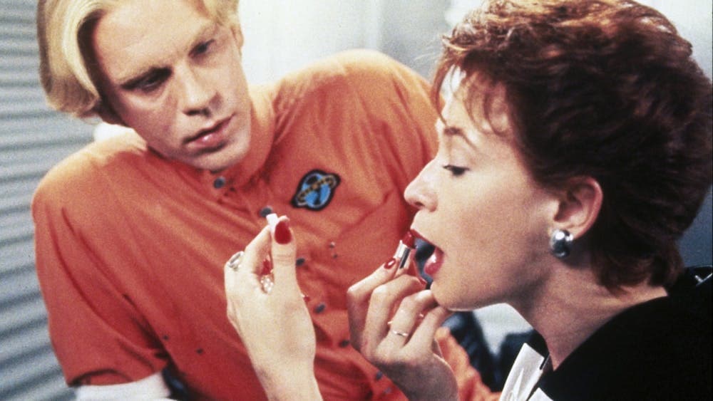 man watching a woman apply lipstick