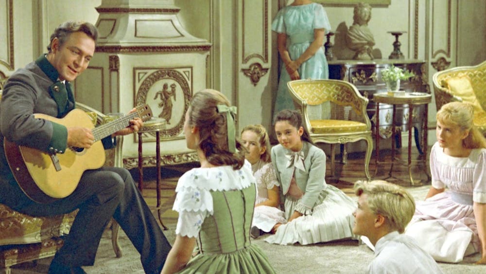 Man sitting in lush interior playing guitar to children sitting on floor