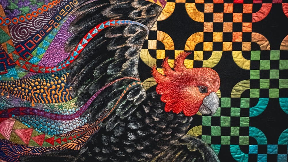 Freedom quilt by Helen Godden of a gang-gang cockatoo in flight with bright details surrounding