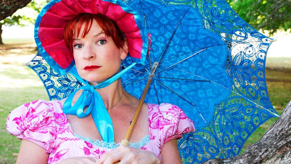 WOman dressed in Jane Austen style costume leaning on a tree