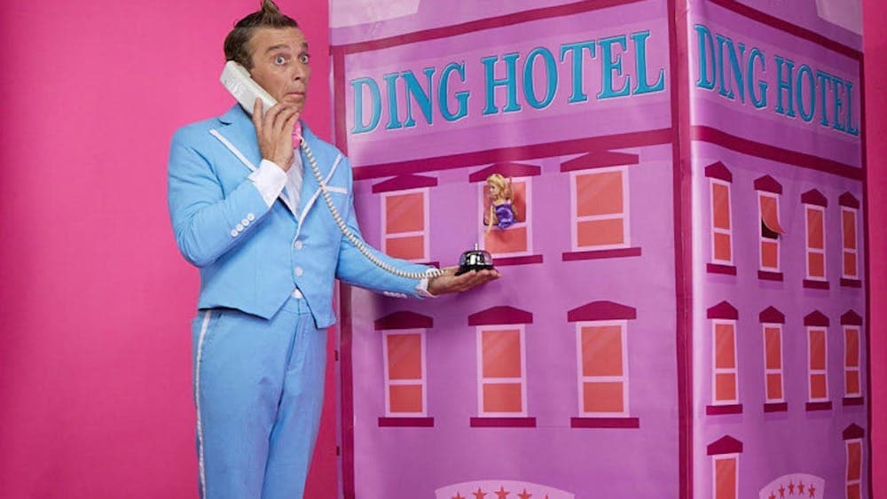 A man holds a prop phone in front of a prop hotel