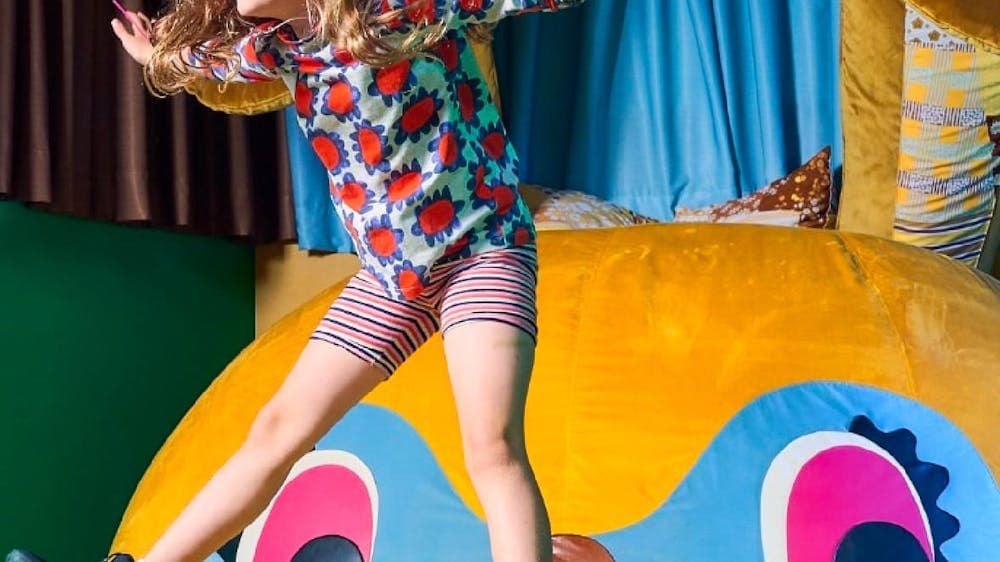 A girl jumps on Bunny Dearest by Beci Orpin. An interactive artwork.