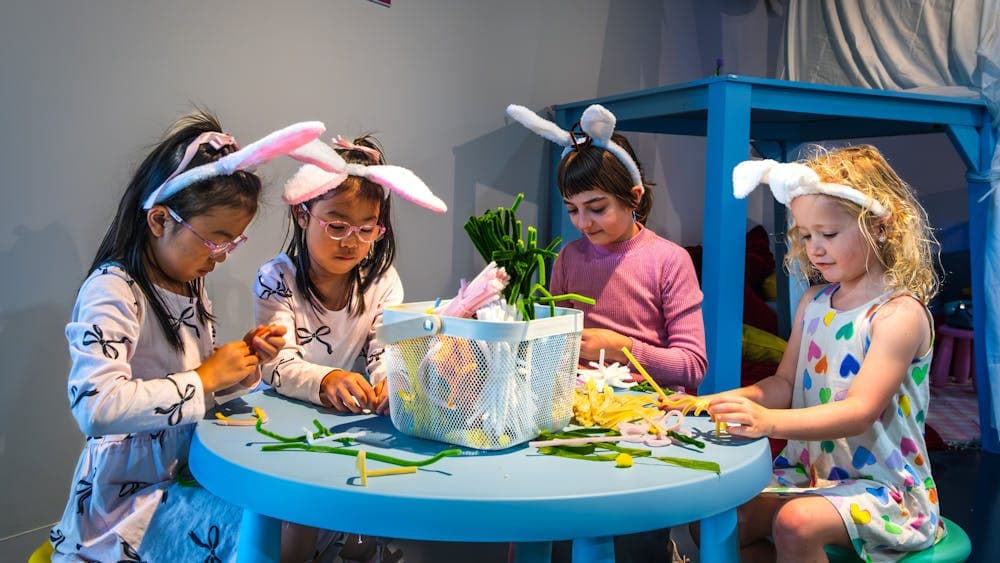 Four children creating objects out of colourful pipe cleaners