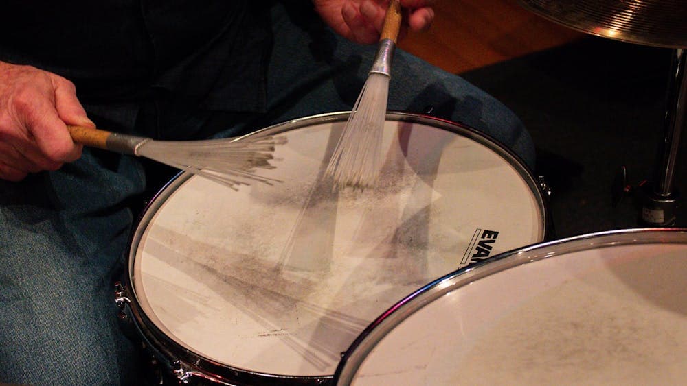 close up of someone playing snare drum with brushes