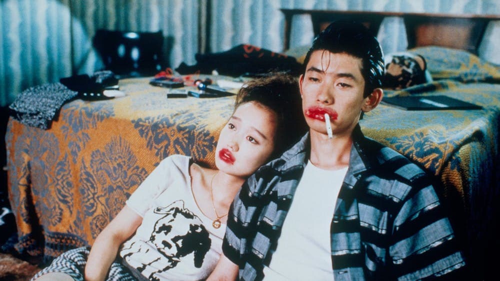 A couple looking exhausted leaning on a bed sitting on floor, both wearing red lipstick