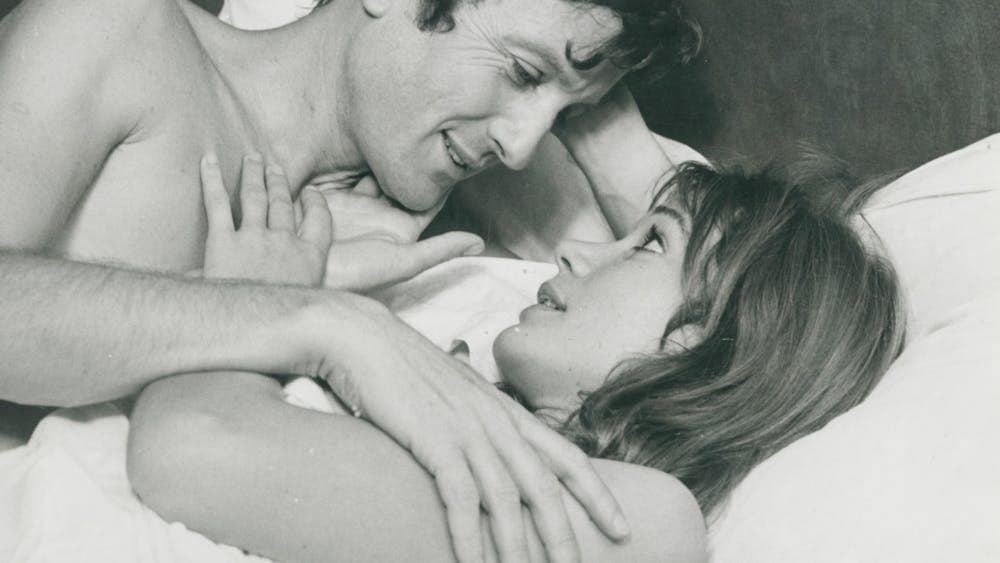 Black and white still of a woman and man in bed looking at each other