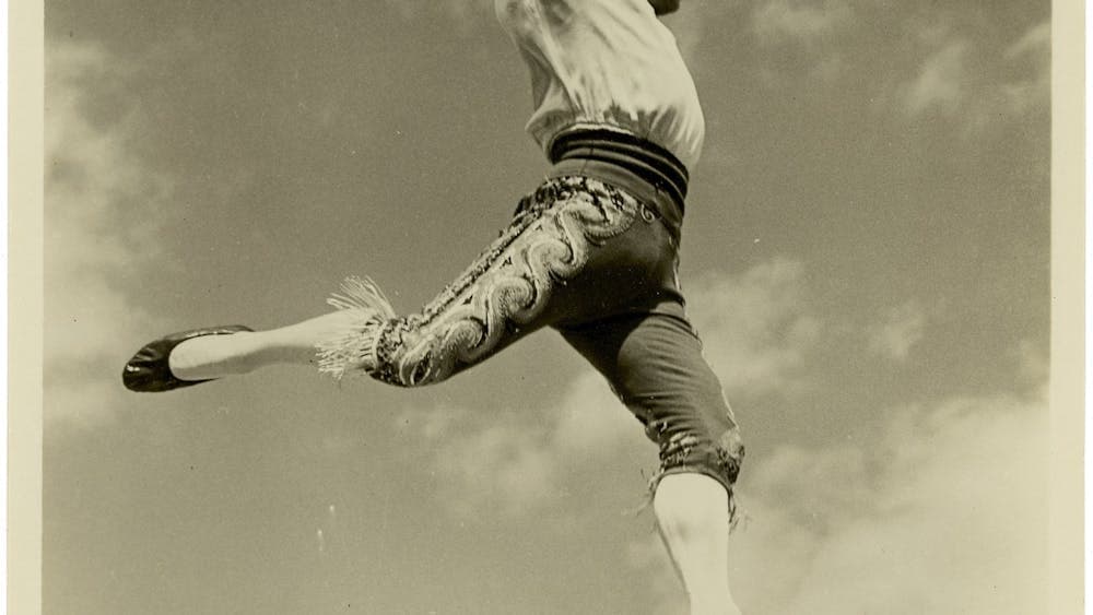 Black and white image of a man walking on a tightrope smiling