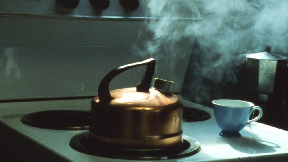 Photo of a kettle boiling on a stovetop and a teacup on the counter