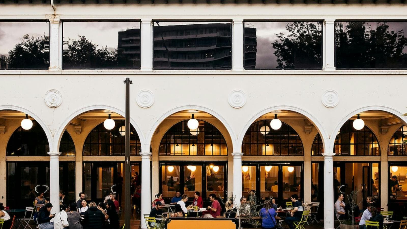 People sitting outside the building at bar tables in colonnade