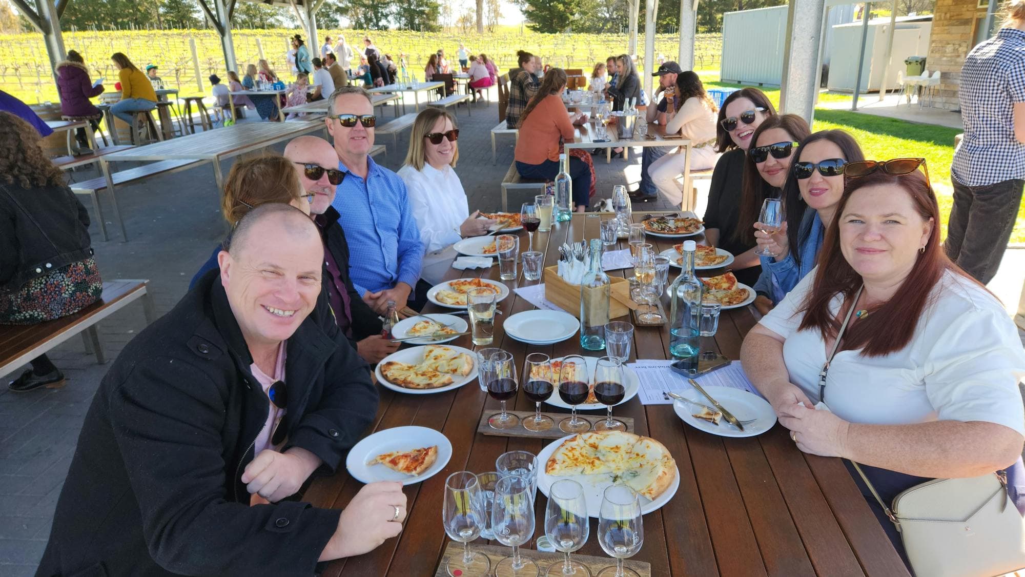 A group of people sitting at a table enjoying a meal together, with a variety of food and glasses of