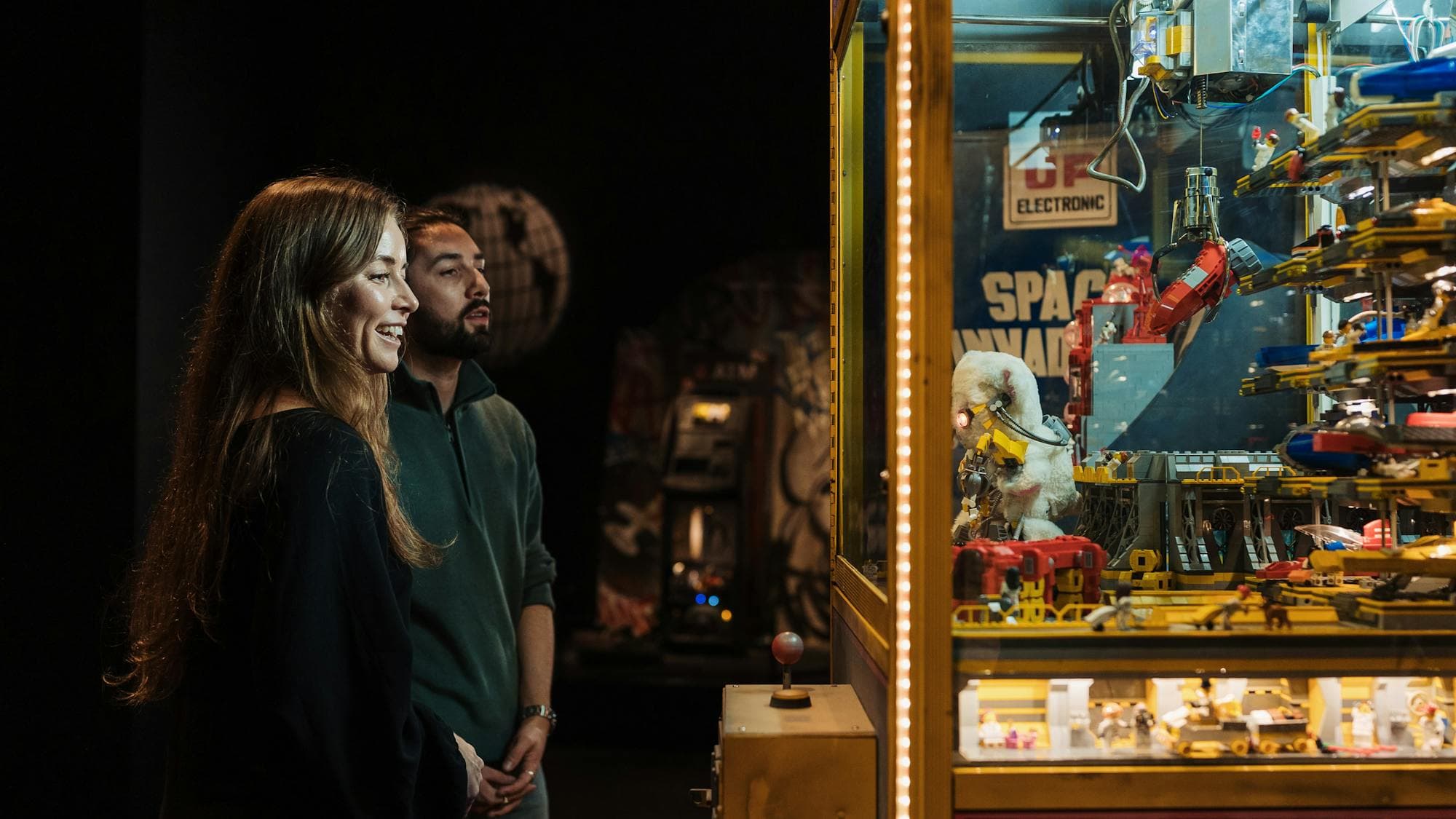 Adult couple enjoying observing a claw machine exhibit in RELICS