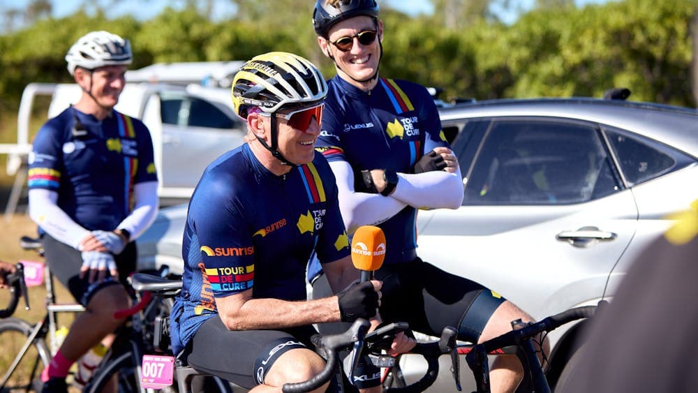 Mark Beretta and Mack Horton casually sitting on their bikes in cycle kit during Signature Tour '25