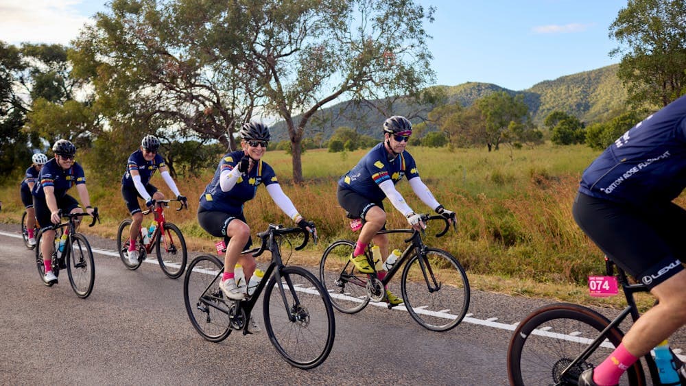 Cyclists riding on the road in a peloton with grass and hills scenic background