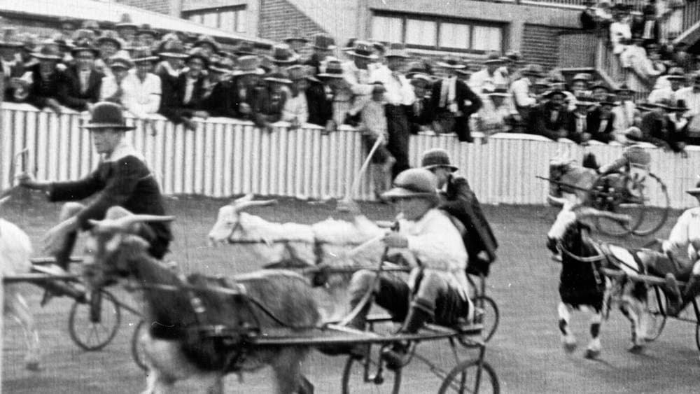 Black and white still from film of a horse race