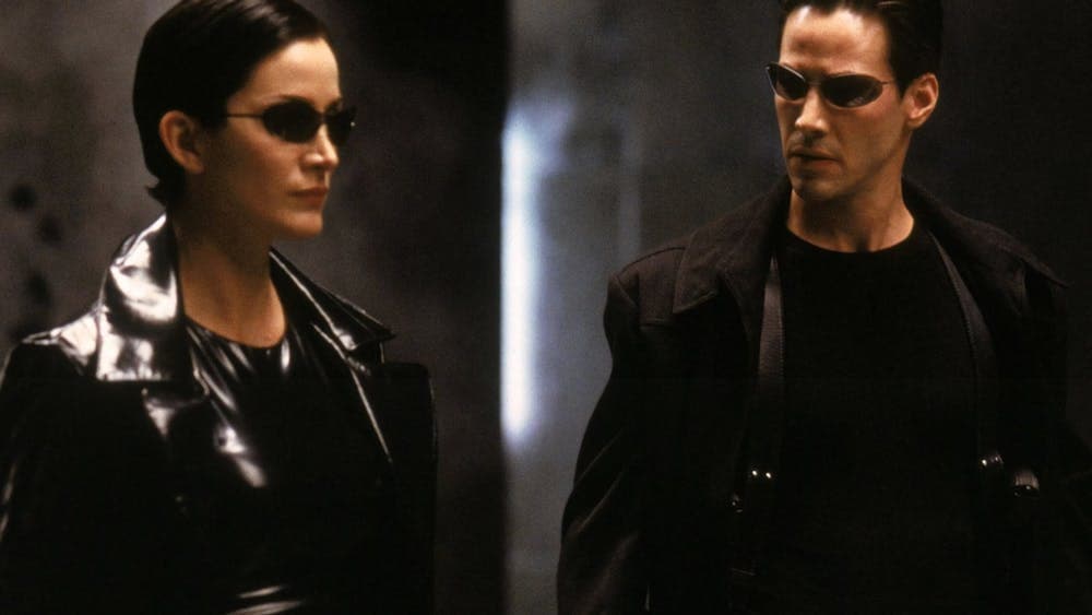 Man and woman standing dressed in black wearing black sunglasses