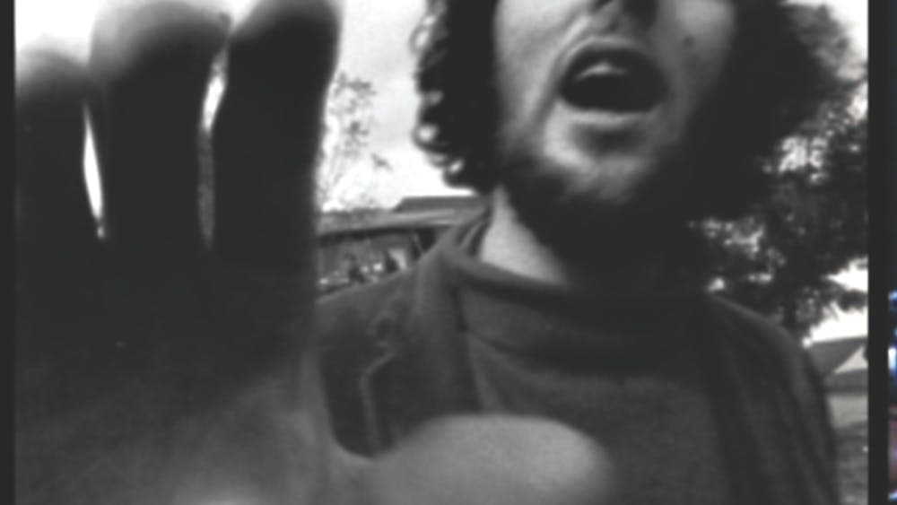 Black and white image of man with hand towards camera and mouth open