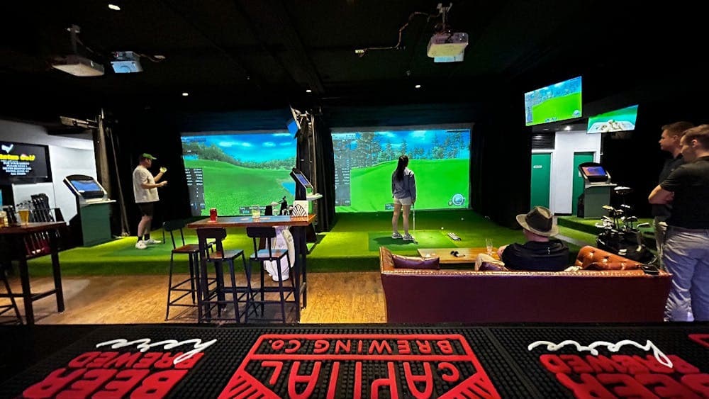 Guests playing indoor golf at Status Golf