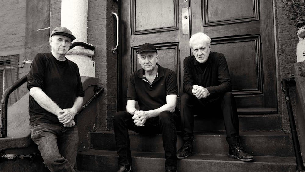 The Necks band members pose on steps, black and white