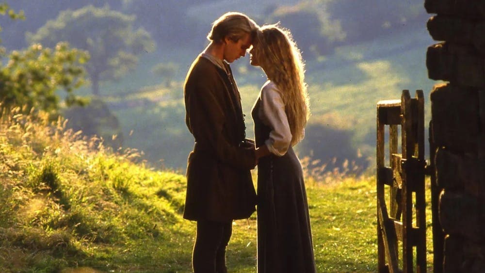 A woman and man embrace with a field in the background