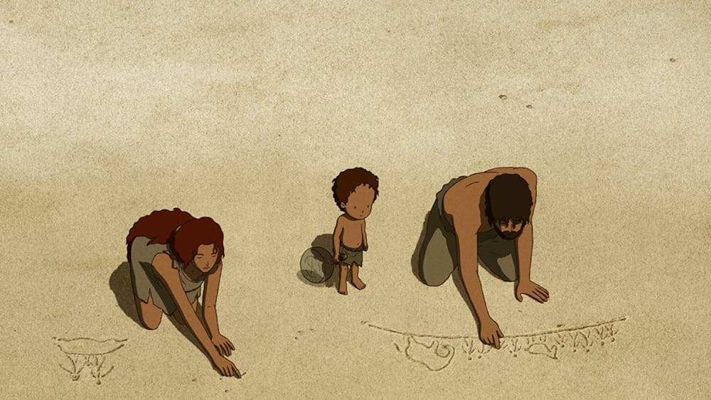 Two adults with a child between them drawing in the sand