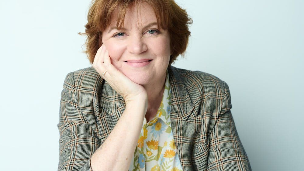 Woman smiles at camera leaning her chin on her hand