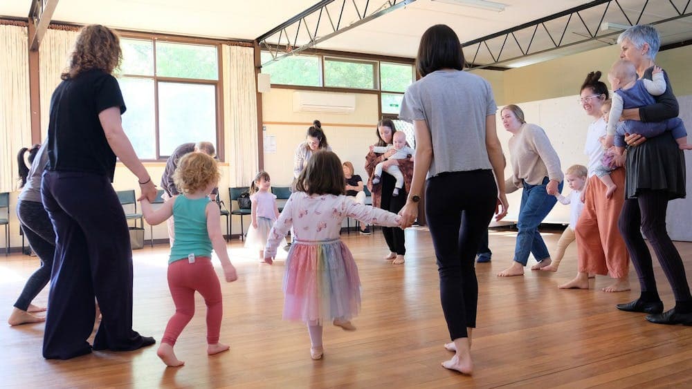 A group of children and their parents participate in a dance workshop