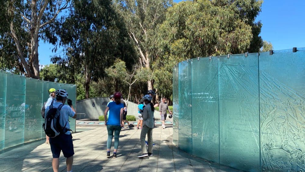 People flanked by the glass walls of the Australian Service Nurses memorial.
