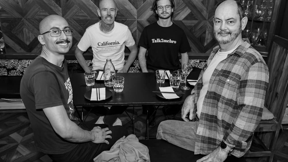 Four men of various ages at a dinner table, smiling at the camera