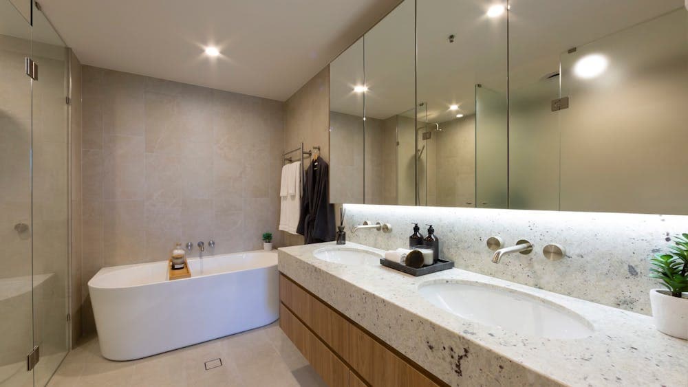 Bright apartment bathroom with a white bathtub, tiled walls, and updated fixtures.