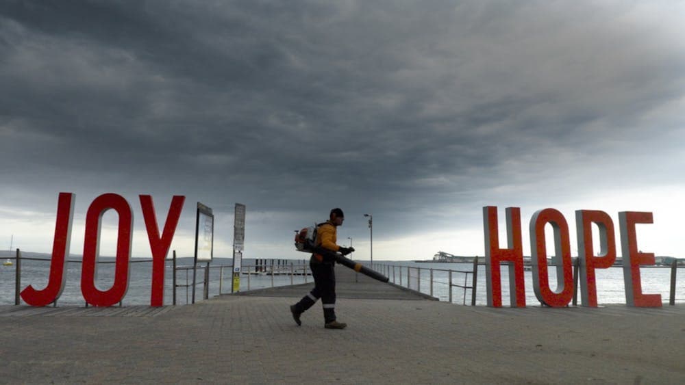 Red large words saying joy and hope on a beach front with a man walking in between