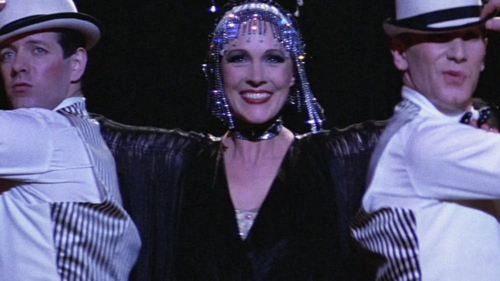Woman performing with two men on either side wearing white hats