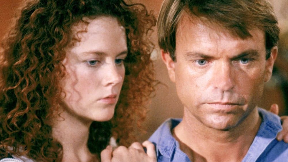 Woman leaning on mans shoulder both looking forlorn
