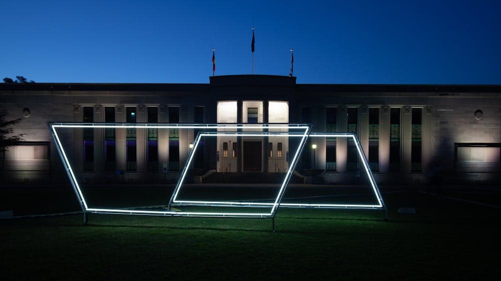 Neon light sculpture on the grass of the National Film and Sound Archive. Photo taken at night.