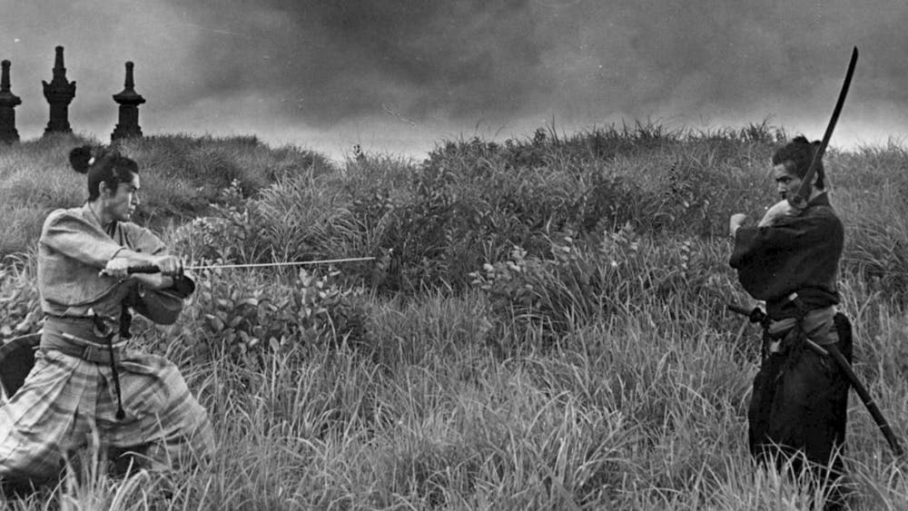 Black and white image in a field with two people wielding swords
