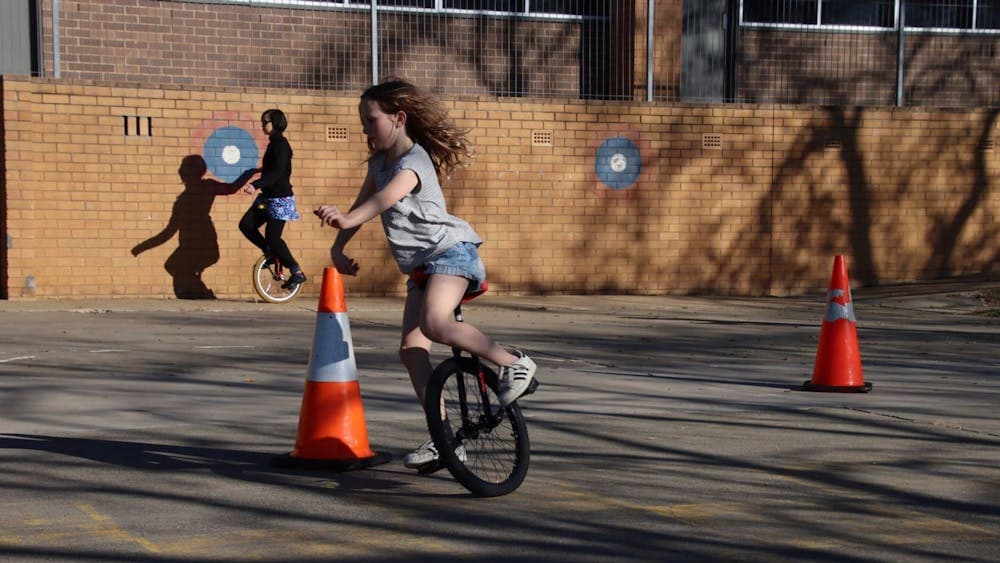 A girl is speeding around a unicycle obstacle course