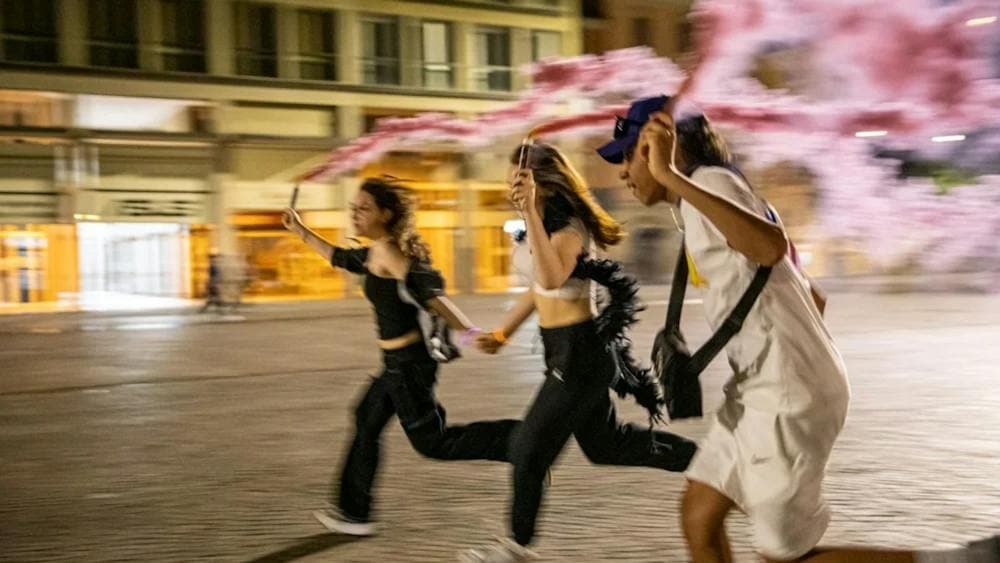 three teenagers running at night with pink flares