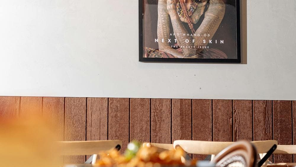 A framed magazine cover featuring a portrait of a traditionally tattooed elder, displayed above a di