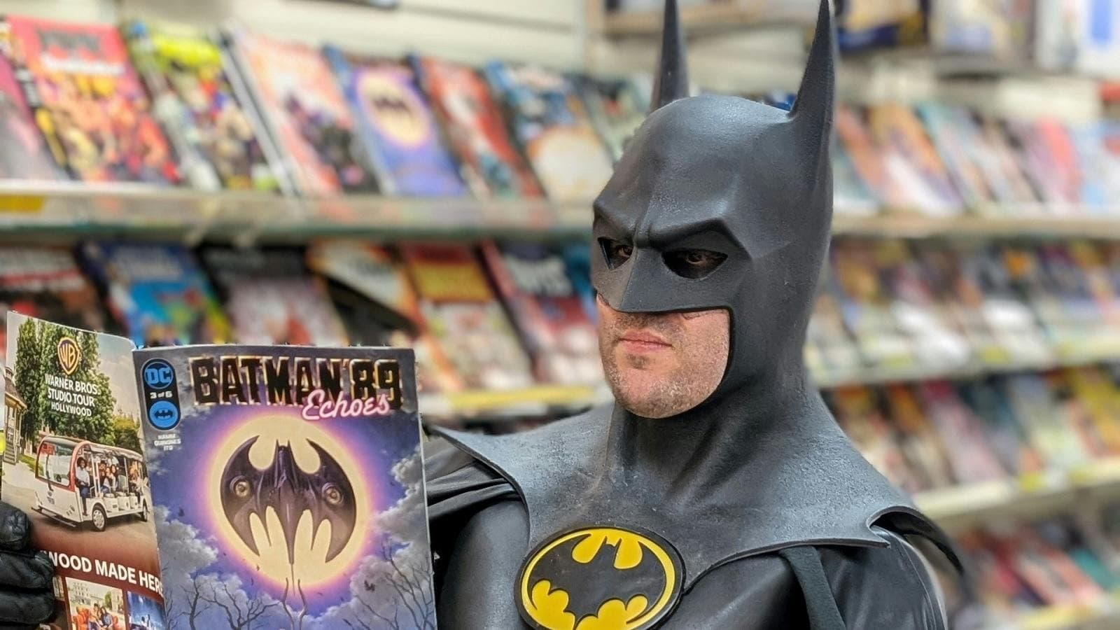 A man dressed as Batman reads a comic book inside a comic shop