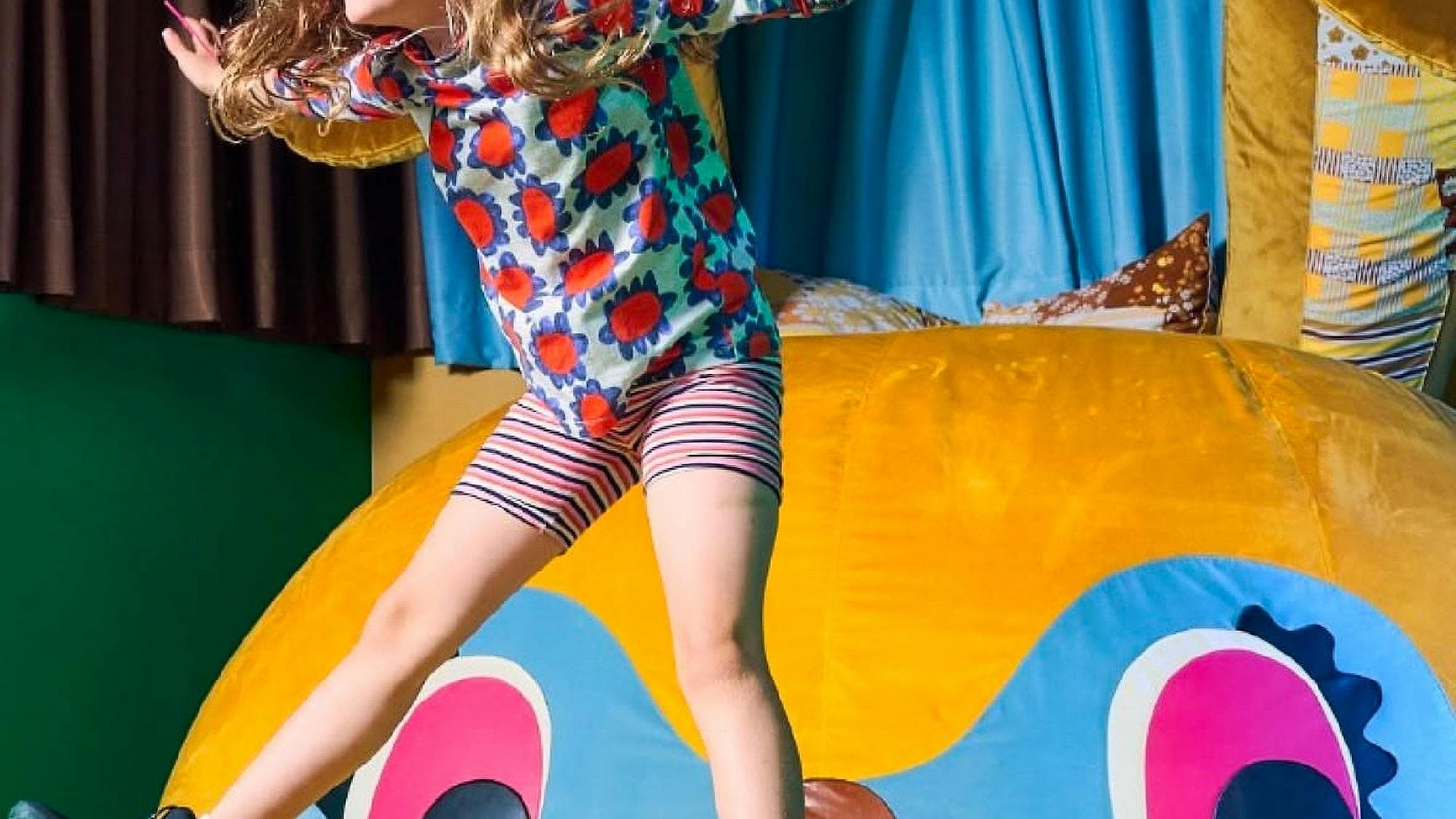 A girl jumps on Bunny Dearest by Beci Orpin. An interactive artwork.