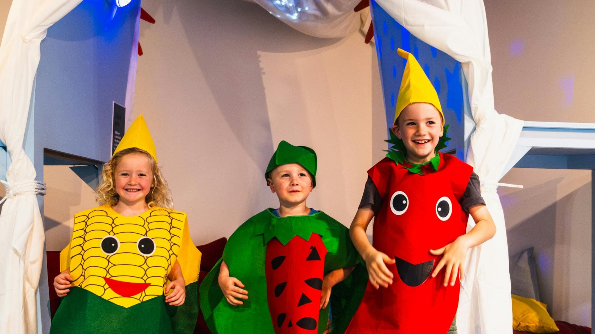 Three children dressed as fruits and vegetables at Hop In